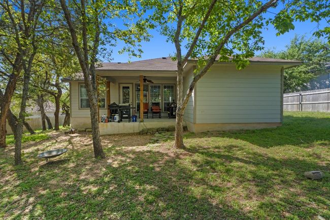Rear view of house with a shaded yard, partial fence, and a patio area | Image 33