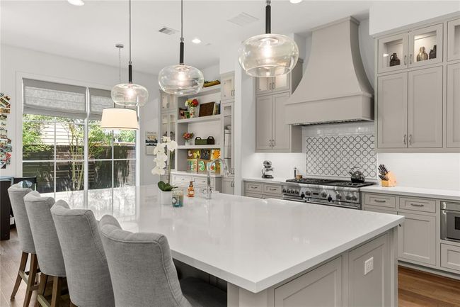 Pendant lighting, Wood paneled Thermador Vent hood, Glass front upper cabinets w/ lighting. | Image 18