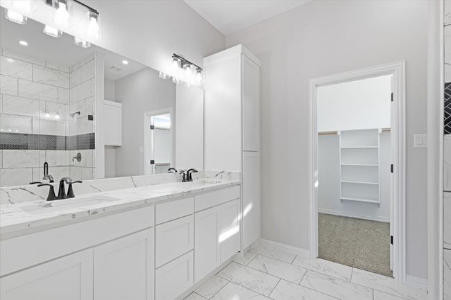 Bathroom with a shower stall, a spacious closet, marble look tiles, double vanity, and recessed lighting | Image 21