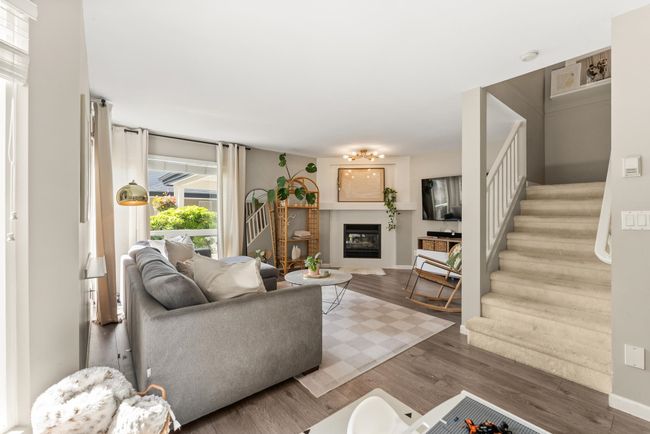 Living area with stairway, wood finished floors, a glass covered fireplace, and baseboards | Image 7