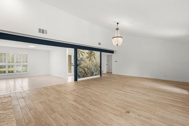 Unfurnished living room featuring light wood-style floors and a towering ceiling | Image 8