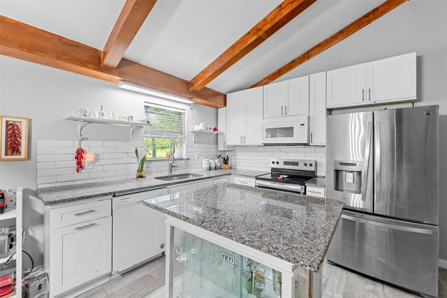 Kitchen with a sink, open shelves, tasteful backsplash, and appliances with stainless steel finishes | Image 7