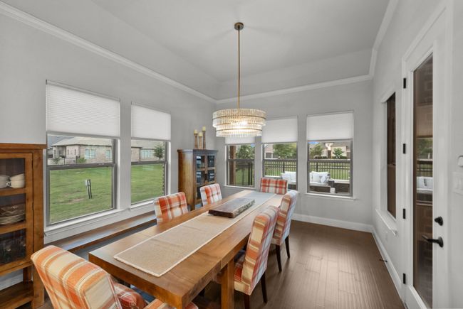 Charming dining room with upgraded chandelier, ornamental molding, wood floors, and a plethora of windows | Image 17