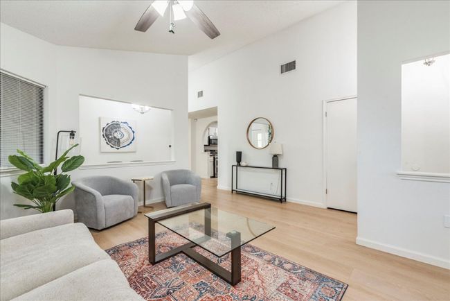Living area with light wood-type flooring, baseboards, visible vents, and a ceiling fan | Image 4