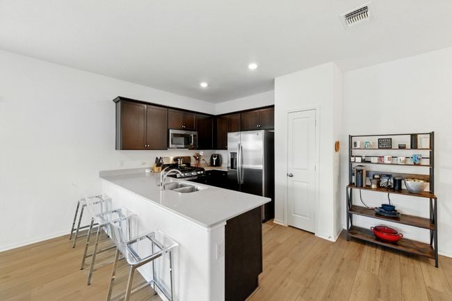 Kitchen featuring appliances with stainless steel finishes, a sink, light wood finished floors, dark brown cabinets, and recessed lighting | Image 11
