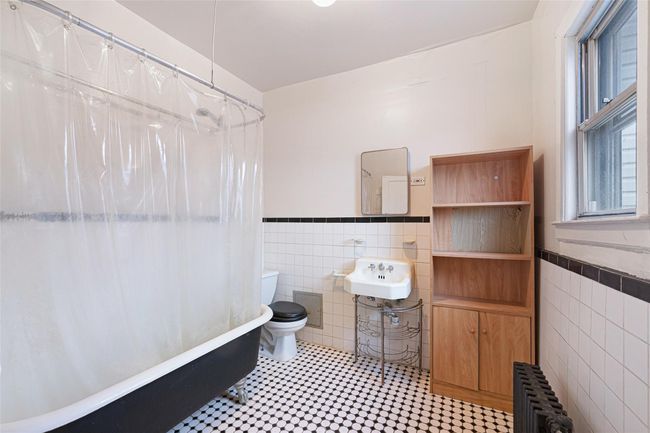 Full bath featuring radiator, toilet, tile walls, and wainscoting | Image 17