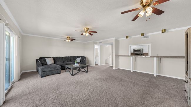 Carpeted living room with ceiling fan, a textured ceiling, and crown molding | Image 7