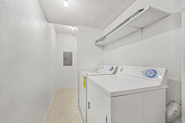 Laundry room featuring electric panel, light floors, a textured ceiling, laundry area, and independent washer and dryer | Image 11