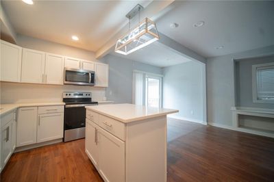 Kitchen featuring pendant lighting, stainless steel appliances, dark hardwood / wood-style floors, and white cabinetry | Image 3