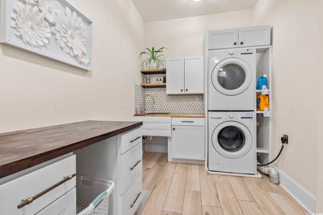 Laundry room featuring cabinet space, stacked washer / drying machine, and light wood-style floors | Image 33