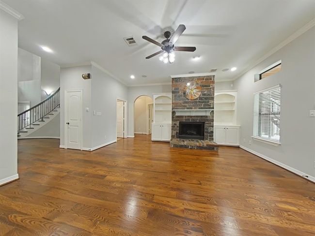 This cozy living room features a stone fireplace, built-in shelves, and hardwood floors. | Image 13