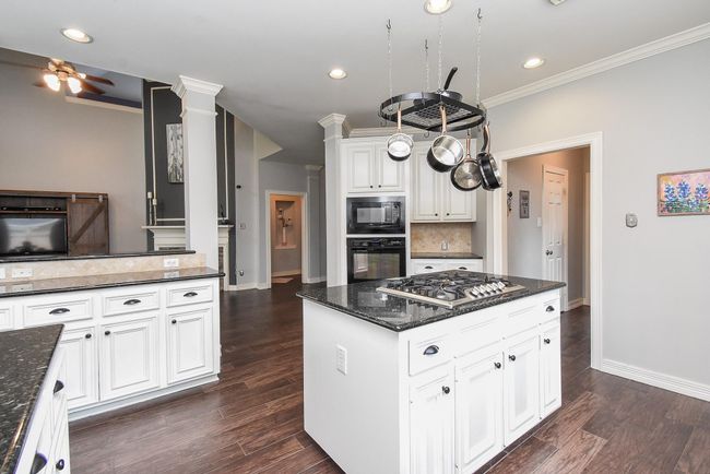 Enter into your HUGE 14' x 14' charming kitchen! It is complete with matching black appliances, miles of gorgeous granite countertops, pristine white cabinets and a stately island with cooktop to help you host the best parties! | Image 7