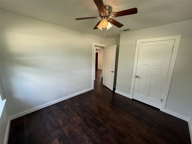 Unfurnished bedroom with dark wood-style floors and a ceiling fan | Image 9