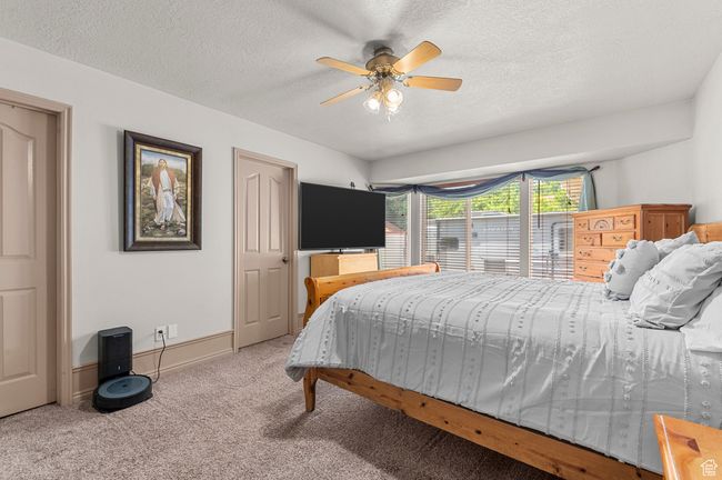 Primary bedroom featuring carpet floors, a textured ceiling, a ceiling fan, and baseboards | Image 14