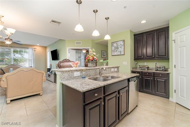 Kitchen featuring a sink, stainless steel dishwasher, light tile patterned flooring, and open floor plan | Image 5