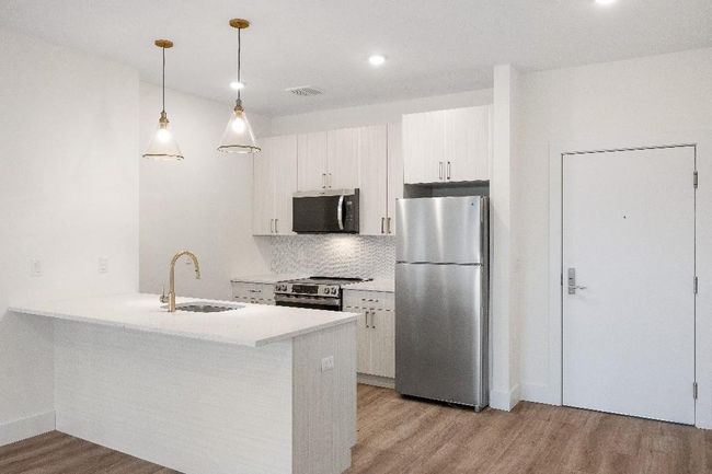Kitchen featuring appliances with stainless steel finishes, a sink, light wood-style flooring, backsplash, and recessed lighting | Image 11