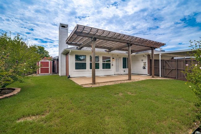 Back of house featuring a pergola, a shed, a patio area, a chimney, and a gate | Image 26