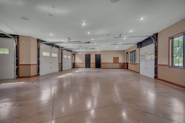 Spacious 5-car garage with a convenient half bath, offering plenty of room for vehicles, storage, and workshop needs. | Image 86