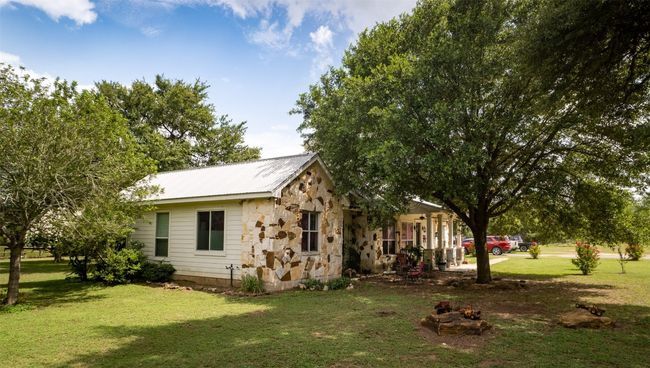 View of front of home with stone siding, a front lawn, and a metal roof | Image 5