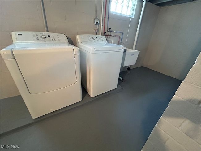 Clothes washing area featuring washer and dryer, concrete block wall, and laundry area | Image 39