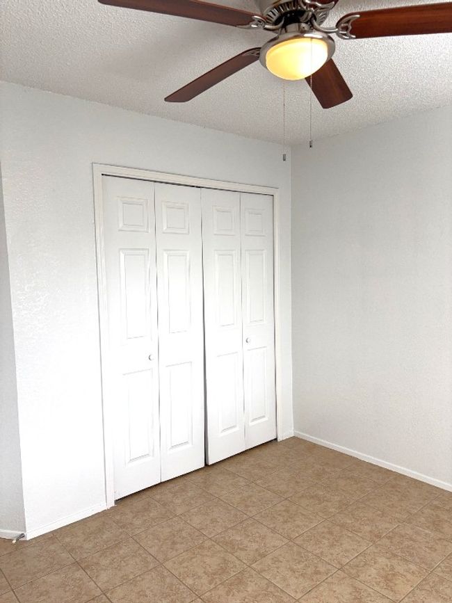 Unfurnished bedroom featuring a closet, light tile patterned floors, a textured ceiling, and ceiling fan | Image 15
