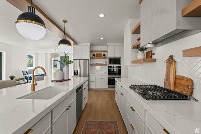 Kitchen with white cabinets, appliances with stainless steel finishes, open shelves, light stone countertops, and decorative light fixtures | Image 20