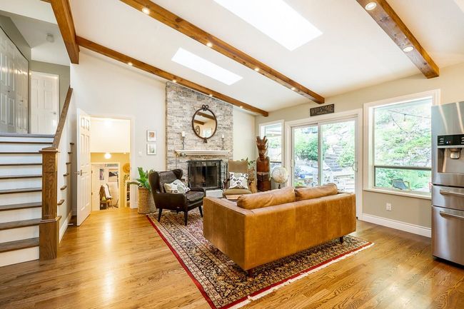 Living area featuring a stone fireplace, a skylight, light wood-type flooring, and stairs | Image 10