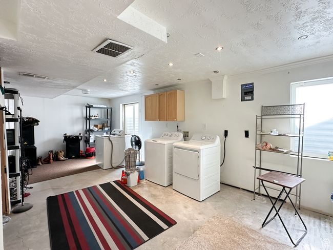 Washroom with electric dryer hookup, washer and dryer, cabinets, and a textured ceiling | Image 15