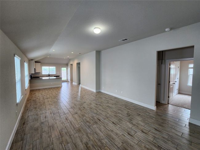 Unfurnished living room featuring dark wood-style flooring, vaulted ceiling, and recessed lighting | Image 4