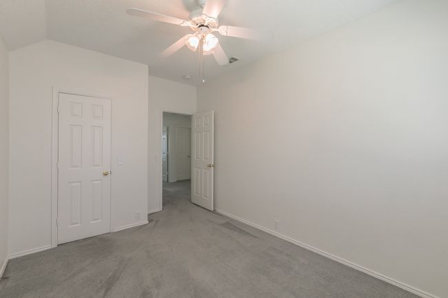 Unfurnished bedroom featuring vaulted ceiling, visible vents, a ceiling fan, baseboards, and light colored carpet | Image 19