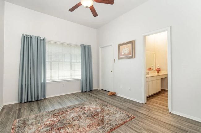 Bedroom with wood finished floors, baseboards, a ceiling fan, and ensuite bathroom | Image 8