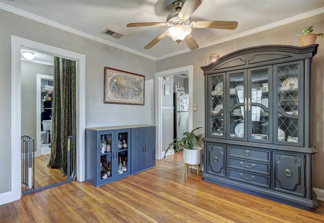Bar with freestanding refrigerator, a ceiling fan, visible vents, and crown molding | Image 9