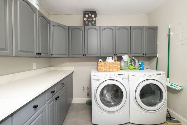 Washroom featuring separate washer and dryer, baseboards, light tile patterned flooring, and cabinet space | Image 19