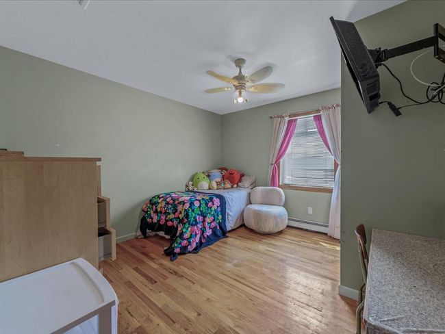 Bedroom featuring a baseboard heating unit, light wood-style floors, and ceiling fan | Image 22