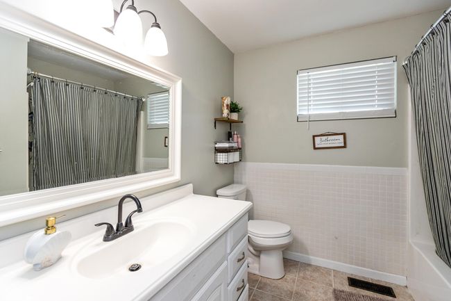 bathroom with vanity, tile patterned flooring, tile walls, and wainscoting | Image 15