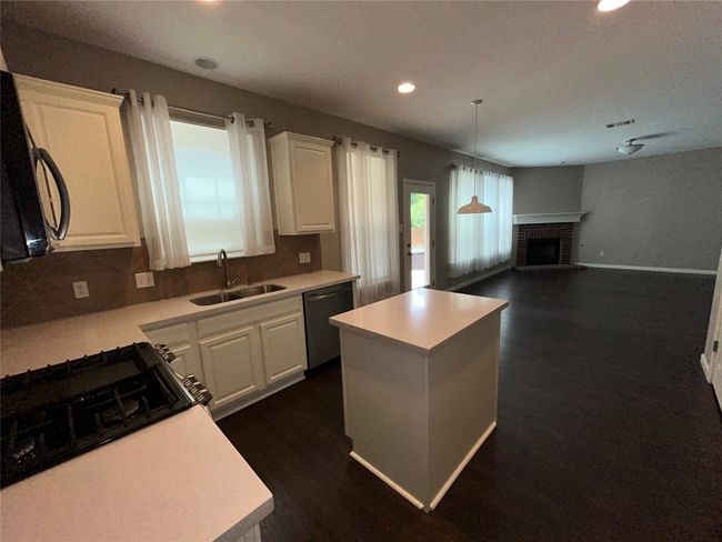 Kitchen featuring stainless steel dishwasher, a sink, recessed lighting, a kitchen island, and white cabinets | Image 14