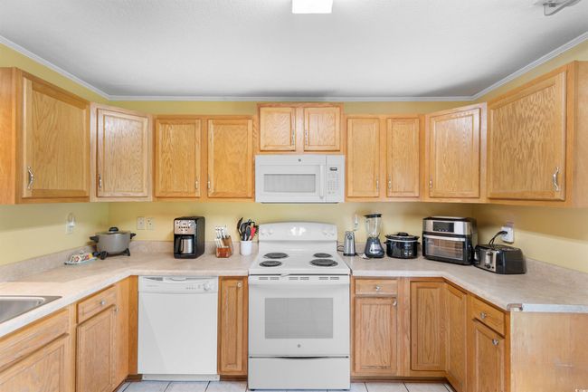 Kitchen with white appliances, light countertops, track lighting, light tile patterned floors, and ceiling fan | Image 7