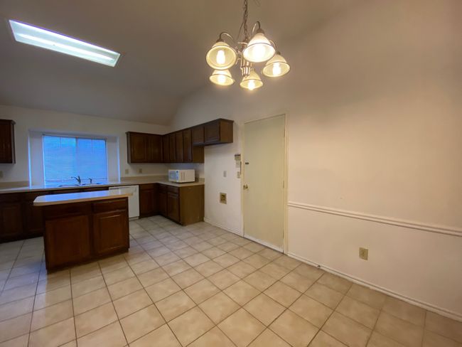 Kitchen featuring lofted ceiling, light countertops, a chandelier, dishwasher, and a center island | Image 9