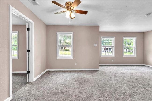 Spare room featuring a wealth of natural light, carpet flooring, visible vents, and baseboards | Image 12