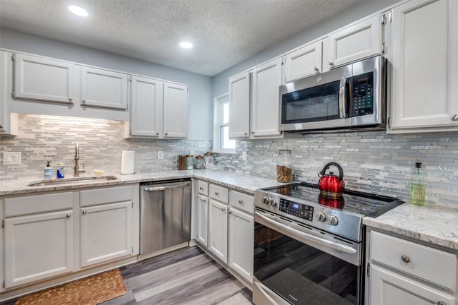 Kitchen featuring appliances with stainless steel finishes, a textured ceiling, recessed lighting, backsplash, and light wood-style flooring | Image 8