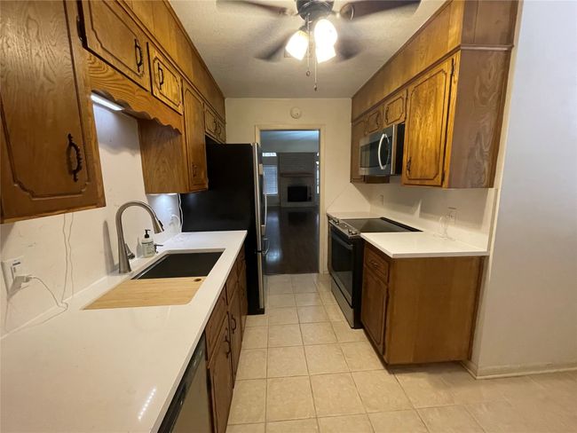 Kitchen with appliances with stainless steel finishes, light tile patterned flooring, a ceiling fan, and light countertops | Image 14