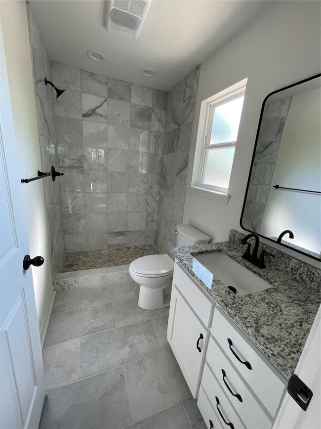 Bathroom with toilet, vanity, visible vents, and tiled shower | Image 10
