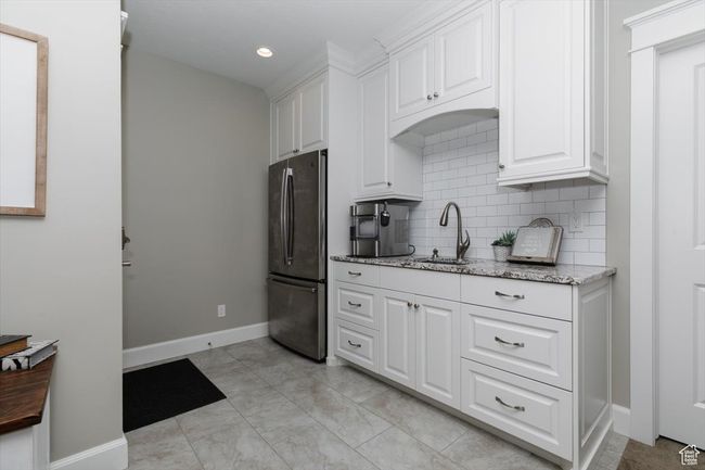 Kitchen with white cabinets, a sink, tasteful backsplash, baseboards, and freestanding refrigerator | Image 57
