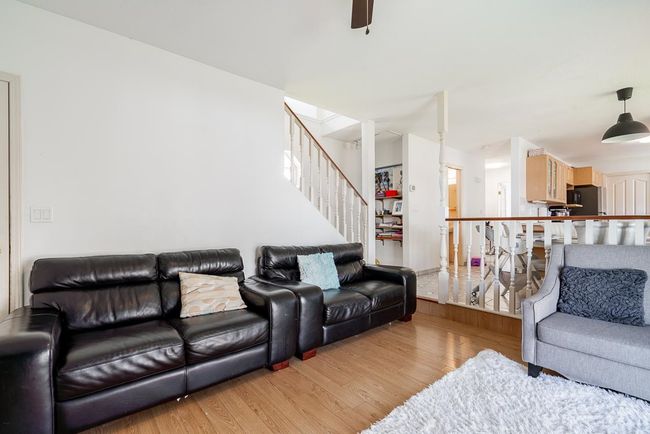Living area with wood finished floors, stairs, and ceiling fan | Image 6