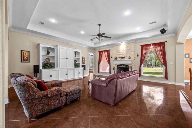 Soaring tray ceiling, recessed lighting and full-height stone fireplace anchor this open gathering space—ideal for both quiet evenings and entertaining. | Image 10