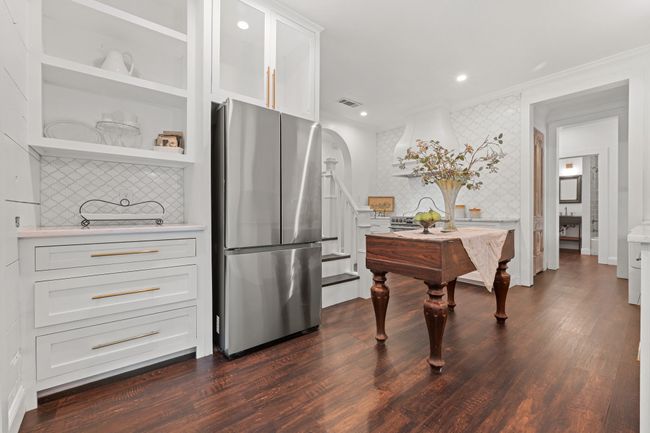 Kitchen with freestanding refrigerator, wallpapered walls, crown molding, light countertops, and white cabinets | Image 14