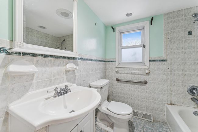 Full bathroom featuring tile patterned floors, toilet, vanity, visible vents, and tile walls | Image 6