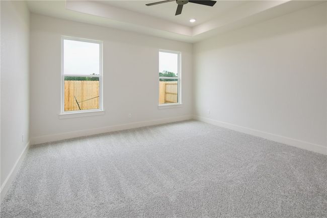 Empty room featuring a tray ceiling, baseboards, a ceiling fan, carpet, and recessed lighting | Image 16