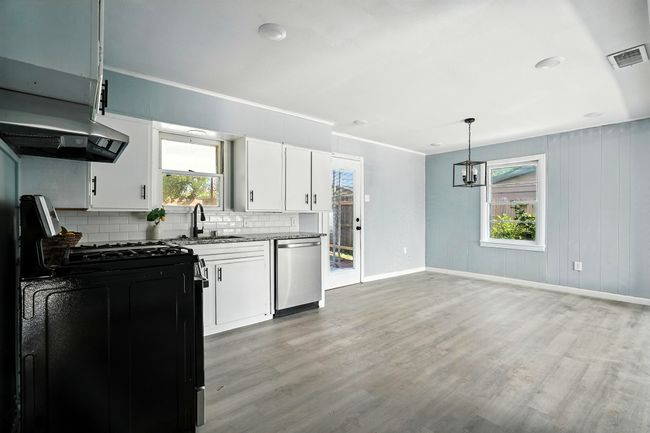 Kitchen featuring dishwasher, range with gas cooktop, decorative backsplash, light wood finished floors, and white cabinetry | Image 9
