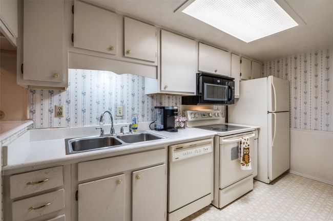 Kitchen with wallpapered walls, light floors, white appliances, light countertops, and wainscoting | Image 8
